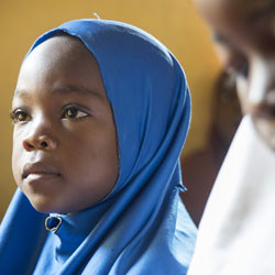 Nigerian girl in classroom listening to teacher.