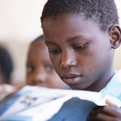 Mozambican boy reading in classroom.