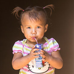 A young girl drinks from a juice box.