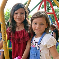 Two girls play on a new playground in El Salvador.