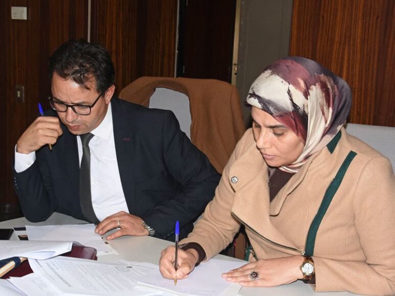 A Moroccan man and woman look over papers at a table.