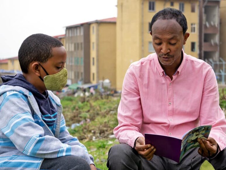 A father and son read a book together