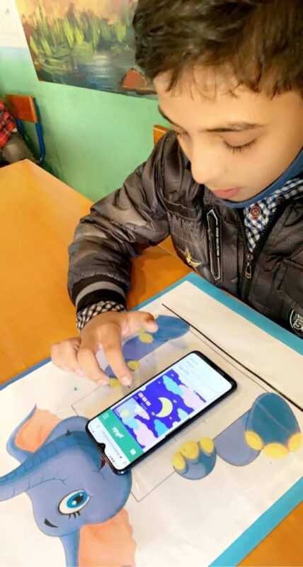 A Moroccan boy reads a story on a smart phone.